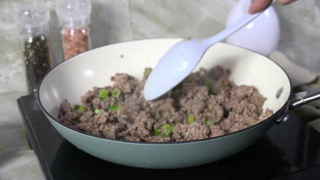 Browning ground beef with onions in a cast iron skillet, slow motion