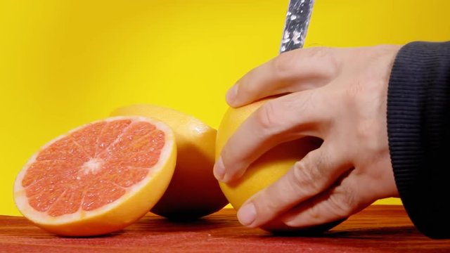 Opening a pomelo (exotic fruit from the Citrus familiy) with a knife. Medium close-up shot.
