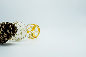 Pine cone and transparent and white Christmas decoration balls with orange and golden details.