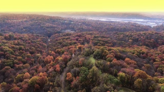 A forward moving aerial establishing shot of the Pennsylvania landscape in late Autumn. Colorful Fall foliage in the distance. Pittsburgh suburbs.  	
