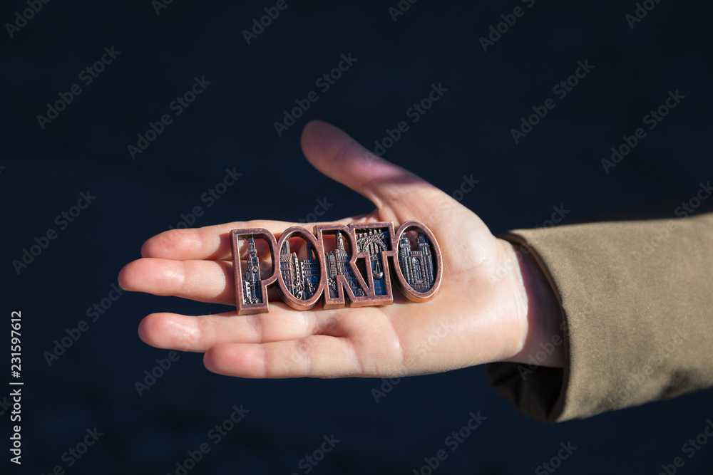 Wall mural Women hand holding Porto magnet souvenir with Porto name in Portugal.