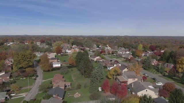 A rising forward aerial flyover establishing shot of a typical Pennsylvania residential neighborhood in Autumn season. Pittsburgh suburbs. Flat picture profile.  	