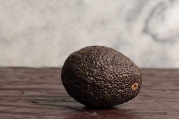 Isolated avocado on dark rustic wood surface with white granite background