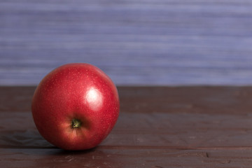 Isolated red mcintosh apple on wooden surface with purple background	