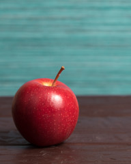 Isolated red mcintosh apple on wooden surface with green and blue background	