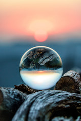 Scenic autumn sunset in Caucasus mountains viewed through glass ball lying on wood pile. Vertical...
