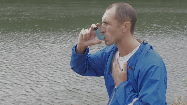 Asthma. A man in nature is choking. A man uses an inhaler.