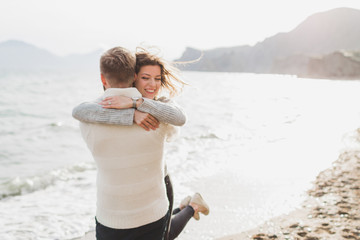 Man and woman in love enjoying together near sea, running by the beach, laughing, kissing and...
