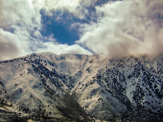The view of snowy mountains and peak with clouds and blue sky