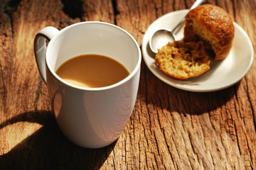 Hot coffee on wooden table, The best instant coffee served with banana cake. Porcelain coffee cup on table with dessert, Selective focus and free space for text. Industrial food and drink concept.