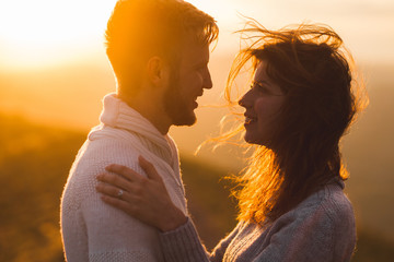 Gentle close-up portrait of man and woman together, happy, looking at each other. Silhouette at beautiful sunset light, wind in hair