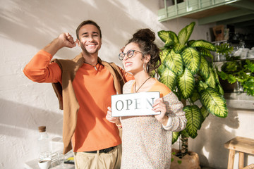 Happy man. Stylish man wearing orange sweater feeling happy after opening restaurant with wife