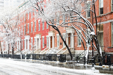 Snow covered winter street scene with view of the historic buildings along Washington Square Park in New York City