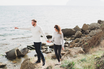 Young couple walking on nordic sea coast with mountain view in spring, casual style clothing...