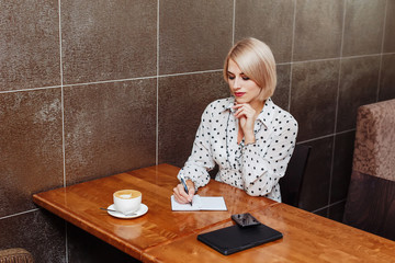 Woman in cafe sitting and writing in notebook