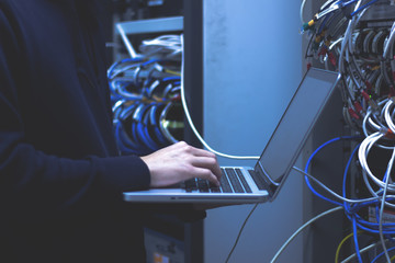 Close up of hands technician working on laptop in data center.Administrator working in data center configure .