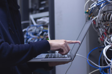 Close up of hands technician working on laptop in data center.Administrator working in data center...
