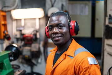 African marine engineer officer in engine control room ECR. He works in workshop with equipment