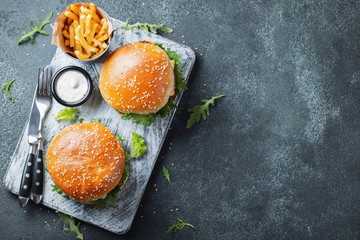 Tasty grilled home made burger with beef, tomato, cheese, cucumber and lettuce on a dark stone...