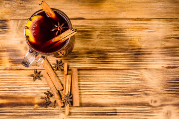 Cup of mulled wine with cinnamon on wooden table. Top view