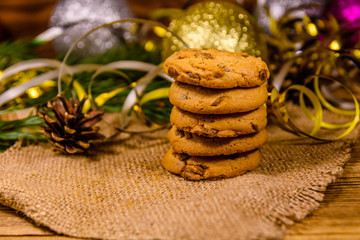 Stack of the chocolate chip cookies on sackcloth in front of christmas decorations