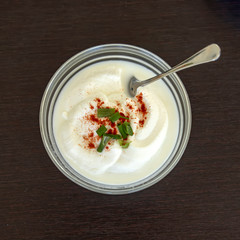 Sour cream in a cup decorated with paprika and green onion slice