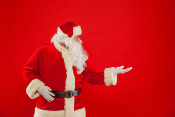 Santa Claus pointing in blank a place, red background