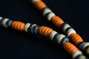 Fragment of a wooden necklace on a dark background close up