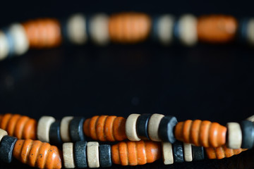 Fragment of a wooden necklace on a dark background close up