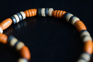 Fragment of a wooden necklace on a dark background close up