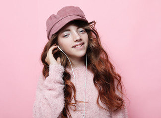 Image of happy teen girl standing isolated on pink background, in pink hat and sweater.