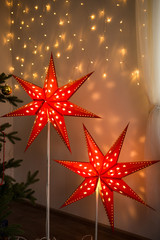 Fototapeta na wymiar Red Christmas star. Christmas cozy home interior decoration, two glowing stars-Christmas home decorations for the New year