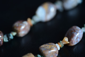 Fragment of a necklace from a natural stone on a dark background close up
