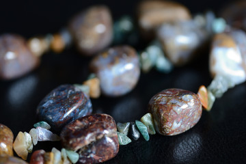 Fragment of a necklace from a natural stone on a dark background close up