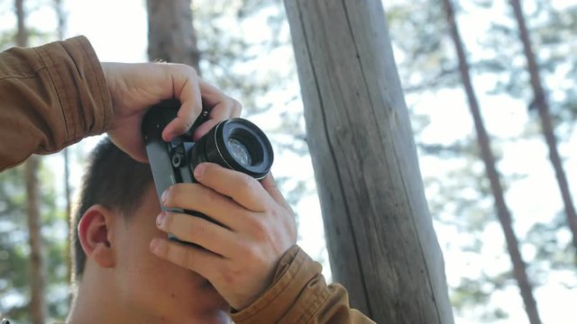 Traveler photographing scenic views in forest by mountain. Man shooting picturesque views. The guy takes photo and video on old retro camera on film. Professional photographer traveler.