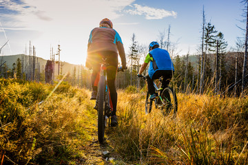 Cycling woman and man at Beskidy mountains autumn forest landscape. Couple riding MTB enduro track....