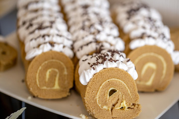 The group of sliced coffee roll with white cream and topped by chocolate in bakery shop. 