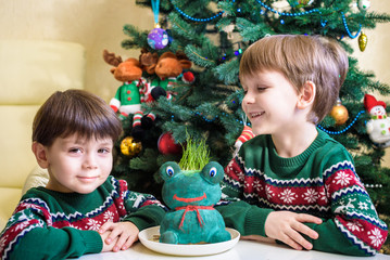 Happy one year old boy lying with many plush toys on blue blanket