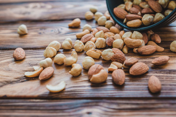 Wooden bowl with mixed nuts ontable. Healthy food and snack. Walnut, pistachios, almonds, hazelnuts and cashews.
