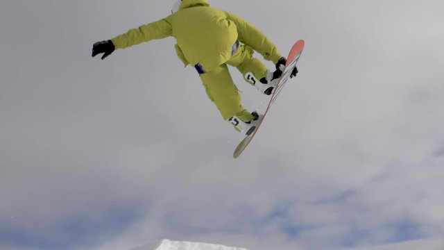 Slow motion - Extreme close up of freestyle snowboarder jumping over kicker
