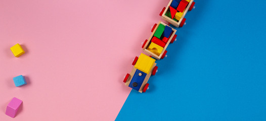 Toy background. Wooden toy train with colorful cubes on pink and blue background
