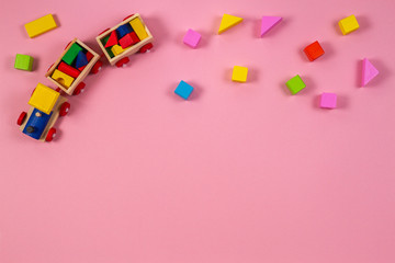 Toy background. Wooden toy train with colorful cubes on pink background