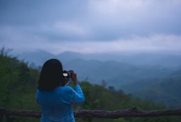 Fototapeta premium Asian woman take a photo at mountain natural view point with fog in morning.freedom lifestyle travel concept.