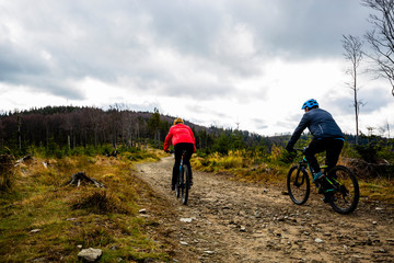 Cycling woman and man at Beskidy mountains autumn forest landscape. Couple riding MTB enduro track. Outdoor sport activity.