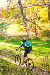 Naklejka premium The girl rides a bike in the autumn park.