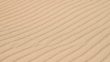 Diagonal waves of sand. Sandy texture background.