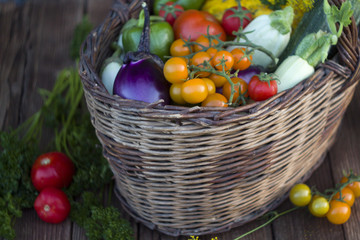 Fresh vegetables in a basket on a rustic wooden table with space for text.