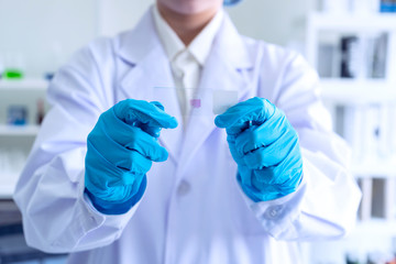 hand of scientist or student or Young female researcher with microscope slide while working on forensic laboratory microscope. education science  research and health concept. ,film tone