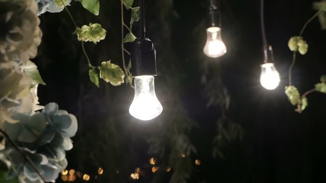 Butiful floral night wedding decorations with soft light of lamps.