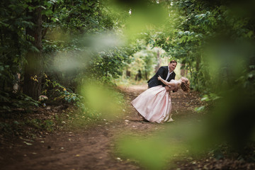 bride and groom dancing in the forest background and sunlight